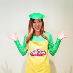 a woman in a green hat and yellow apron with her hands out to the side