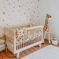 a giraffe standing next to a baby crib in a room with white walls