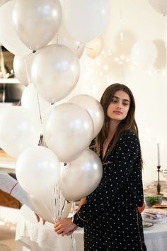 a woman standing next to a bunch of white balloons