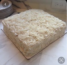 a cake with white frosting sitting on top of a counter