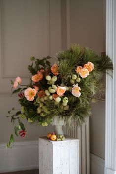 a vase filled with flowers sitting on top of a white table next to a wall