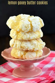 lemon gooey butter cookies stacked on top of each other in a pink plate with red and white checkered tablecloth