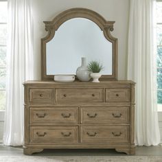 a dresser with a mirror and vase on top