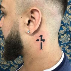 a man with a small cross tattoo on his left side behind the ear is looking at something