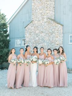 a group of women standing next to each other in front of a building with rocks on it