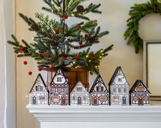 a small christmas tree in a pot on top of a mantel with miniature houses