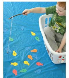 a young boy is sitting in a laundry basket and playing with magnets on the floor