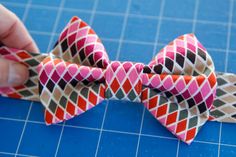 someone is making a bow tie out of fabric on a cutting board with blue background