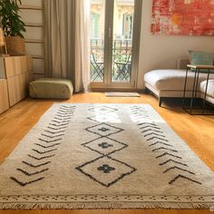 a living room with wooden floors and a large rug on the floor in front of a sliding glass door