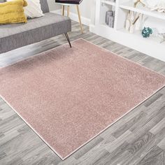 a living room with a gray couch and pink rug