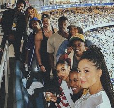 a group of people standing next to each other in front of a stadium filled with fans