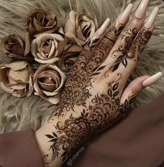 a woman's hand with henna on it and flowers in front of her