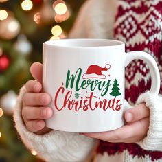 a person holding a white coffee mug with merry christmas written on the front and bottom