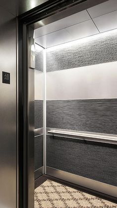 an empty elevator with the door open and carpeted flooring on the ground next to it