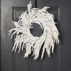 a white wreath hanging on a black door