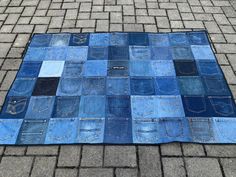 a blue patchwork rug made out of old jeans on the ground in front of a brick sidewalk