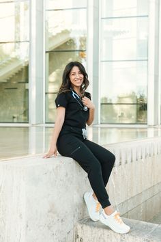 a woman sitting on top of a cement wall next to a building