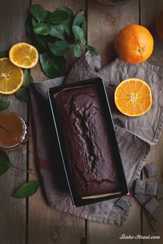 a loaf of cake sitting on top of a table next to oranges and other fruit