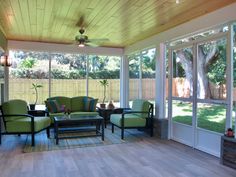 a sun room with green chairs and tables in the middle of an open patio area