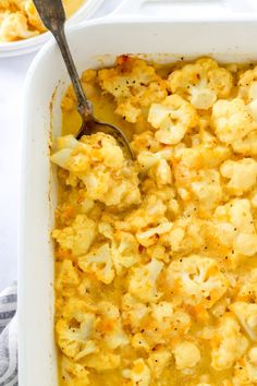 a white casserole dish filled with cauliflower and topped with a spoon