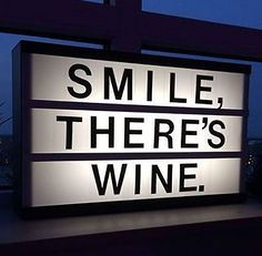 a lighted sign that says smile, there's wine on the window sill