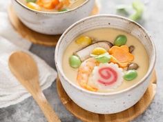 two white bowls filled with soup and vegetables