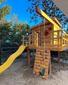 a wooden play structure with a slide and climbing frame in the sand at a playground