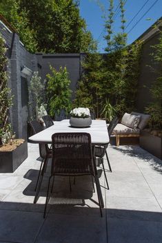 a table and chairs on a patio with trees in the backgroung area