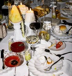 a table is set with wine, food and desserts for an elegant dinner party