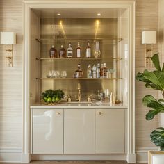 a kitchen with white cabinets and shelves filled with bottles, glasses, and other items