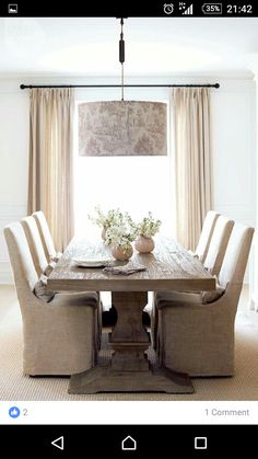 a dining room table with six chairs and a vase on the centerpiece in front of it