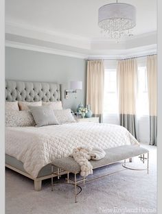 a bedroom with gray walls and white bedding in the center, along with a chandelier hanging from the ceiling