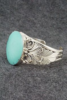 This stunning turquoise and sterling silver bracelet was made by Navajo silversmith Gilbert Smith. The back is partially signed RB and .925.Size: 5 3/8" (will fit up to a 6 3/8" wrist)Gap: 1"Width: 1 3/8"Cuff Width: 1/2"Free shipping on all orders! We ship with USPS and always include tracking. All orders ship within a day of payment.Returns are accepted up to 30 days after you receive your order. Just send us a message. Our shop offers cash back or store credit. The item must be returned in new Elegant Sterling Silver Bracelet With Turquoise, Elegant Turquoise Engraved Sterling Silver Bracelet, Elegant Engraved Turquoise Sterling Silver Bracelet, Elegant Turquoise Bracelet With Inlay, Elegant Turquoise Inlay Bracelet, Elegant Turquoise Oval Sterling Silver Bracelet, Southwestern Turquoise Bracelet With Polished Finish, Southwestern Turquoise Bracelets With Polished Finish, Turquoise Carved Bohemian Jewelry