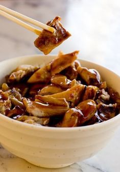 a bowl filled with meat and chopsticks on top of a marble countertop