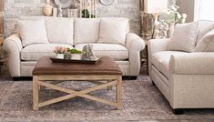 a living room with two couches and a coffee table in front of a brick wall