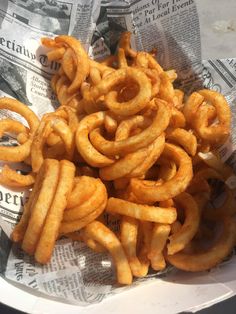 a pile of onion rings sitting on top of a white paper plate covered in newspaper