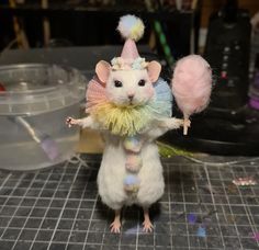 a toy mouse with a party hat and pom - poms