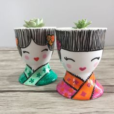 two small pots with plants in them on a table