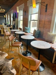 tables and chairs are lined up against the brick wall in this restaurant with exposed ceilings