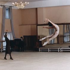 two people in a dance studio one is jumping and the other is doing a handstand