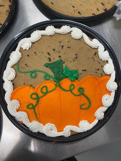 there is a cake decorated to look like a pumpkin on top of some pies