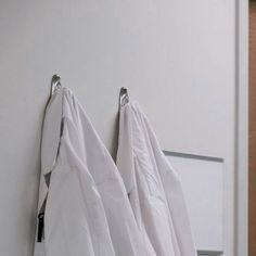 three white towels hanging on the wall next to each other