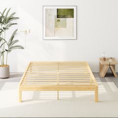 a wooden bed frame sitting on top of a white floor next to a potted plant