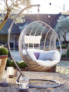 an outdoor swing chair in the middle of a graveled area next to a potted plant