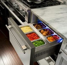 an open drawer in the middle of a kitchen counter with food items on it, including salads and condiments