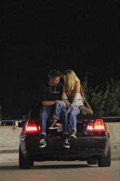 two people sitting on the back of a car