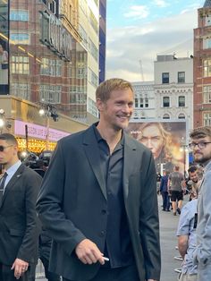 a man in a suit and tie walking down the street with other people behind him