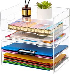 a stack of office supplies with a pen and notebooks on the top one shelf