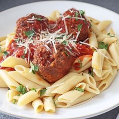 meatballs and pasta on a plate with parmesan cheese sprinkled on top