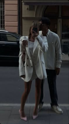 a man and woman standing next to each other on the street